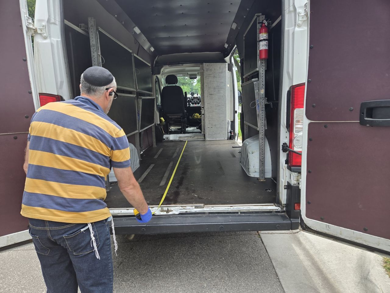 Driver measuring cargo floor length from the rear of the van